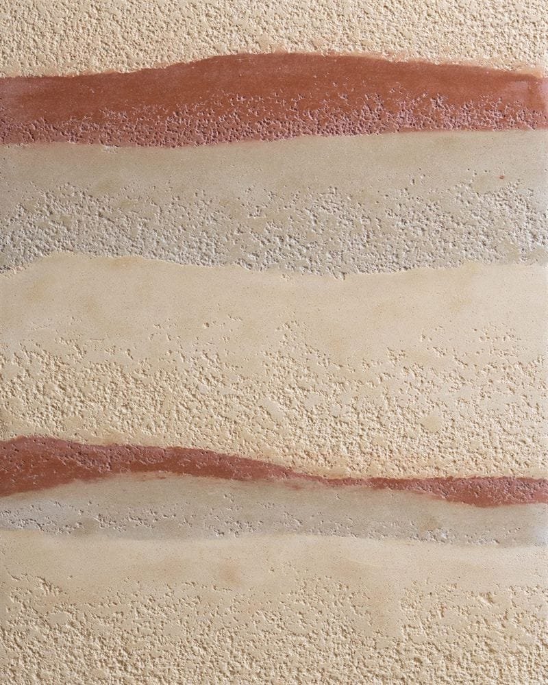 Rammed earth finish clay plaster showing horizontal strata in warm earth tones